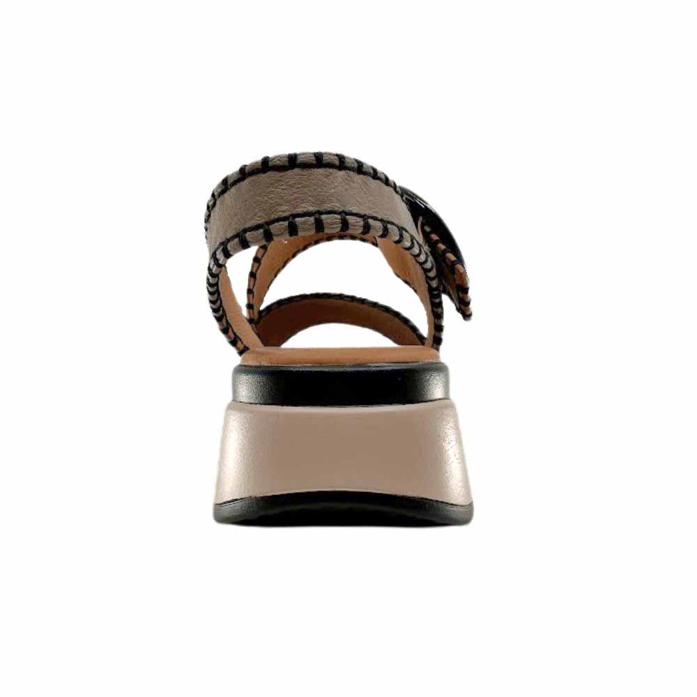 The back view of a sandal with black, taupe and tan leather straps with stitched edged detailing, set on a beige platform sole, against a white background.