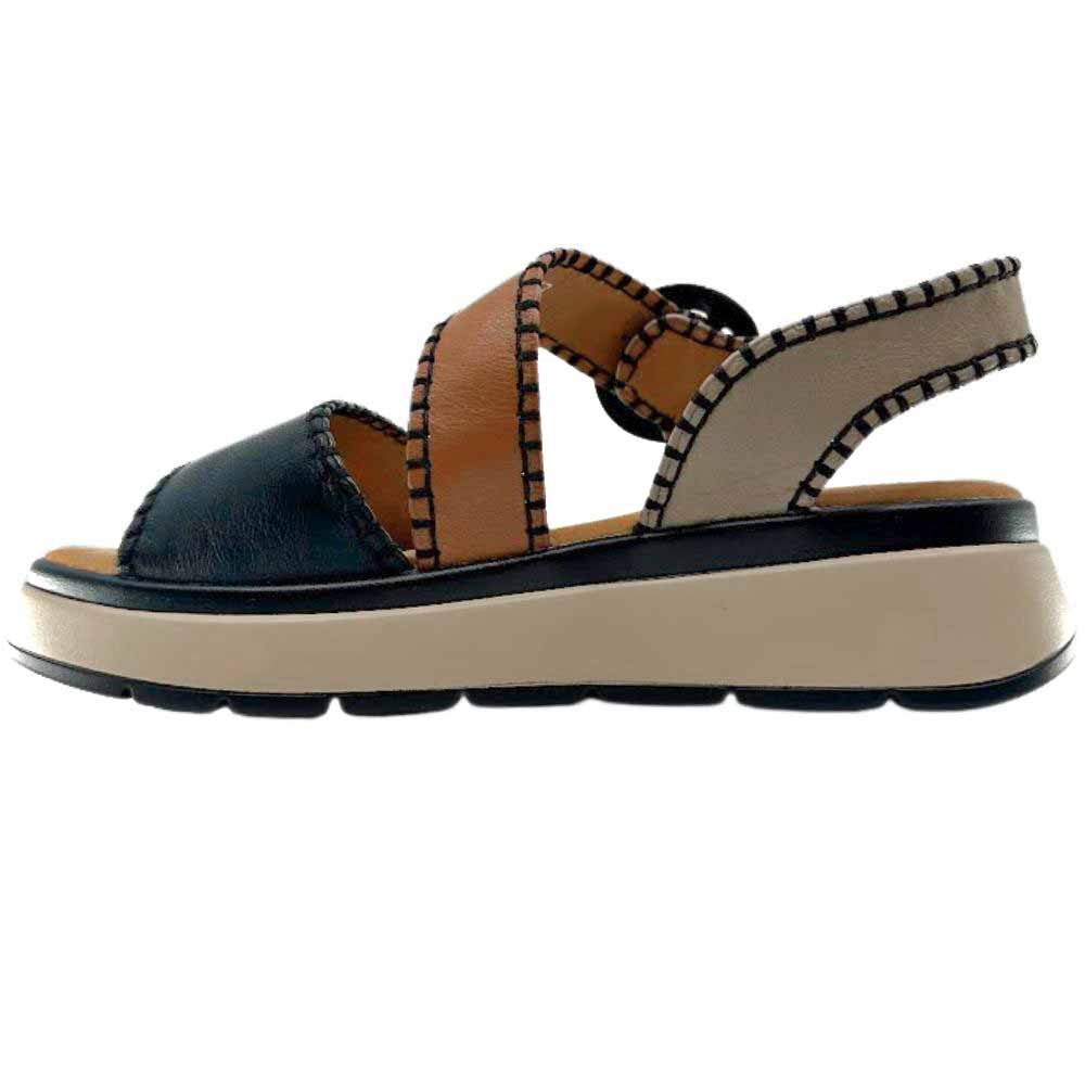A sandal with black, taupe and tan leather straps with stitched edged detailing and a round buckle, set on a beige platform sole, against a white background.