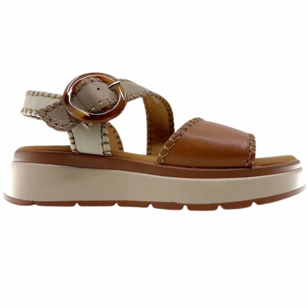 A sandal with tan, taupe and cream leather straps with stitched edged detailing and a round buckle, set on a beige platform sole, against a white background.