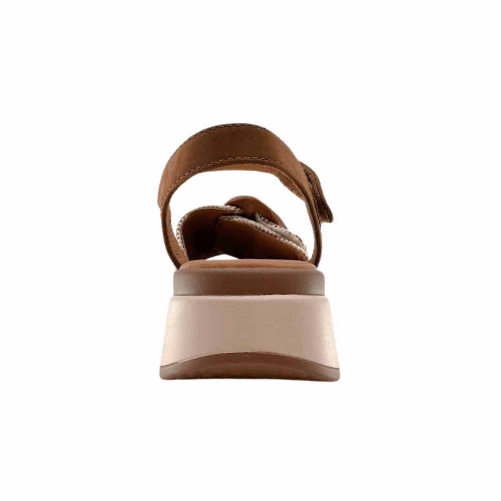 The back view of a sandal with a tan ankle strap and a tan and beige platform sole, against a white background.