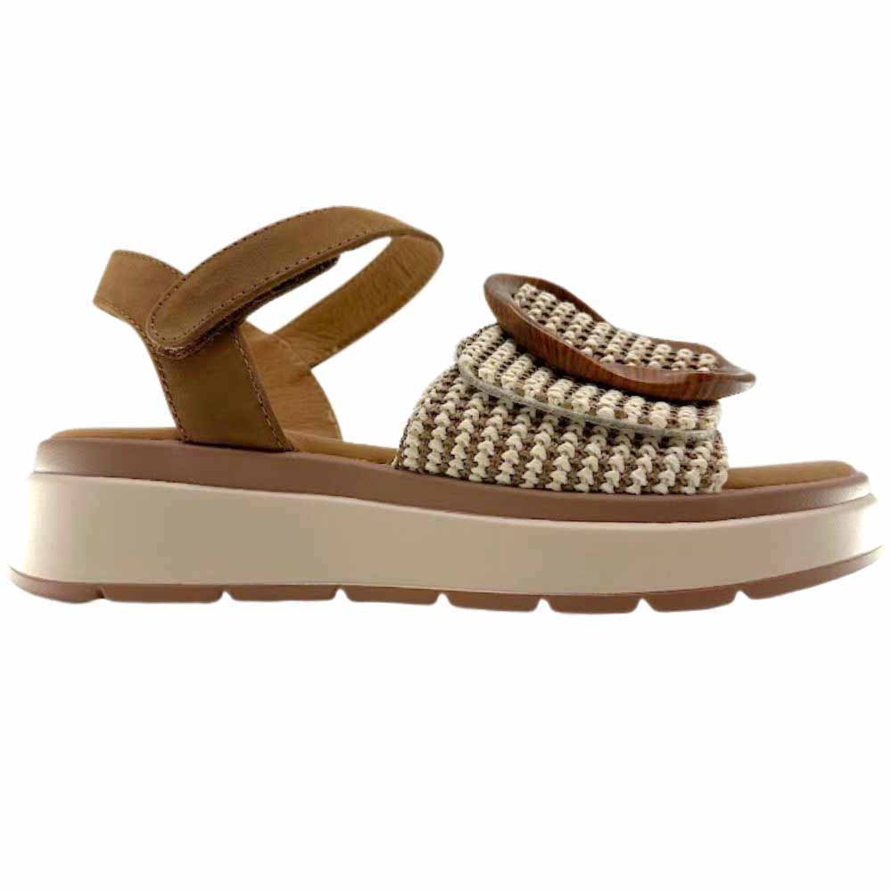 A sandal with a tan and cream woven strap across the vamp with a statement oversized buckle, a tan ankle strap and a beige platform sole against a white background.