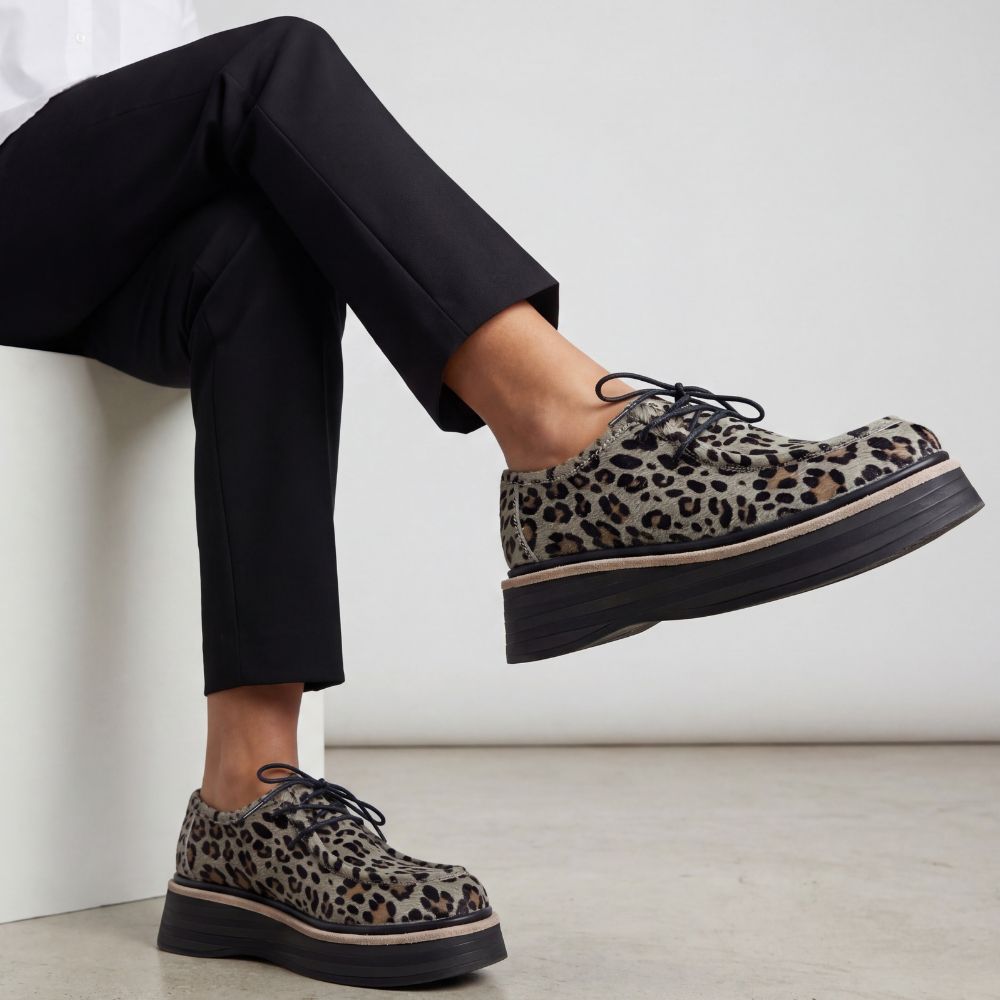 Leopard print shoes worn with black pants on a light background