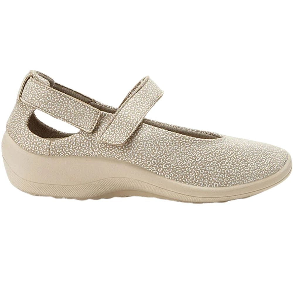 A single women's Mary Jane style shoe in beige with a textured speckled pattern and a hook-and-loop strap closure, shown from a side profile on a white background.