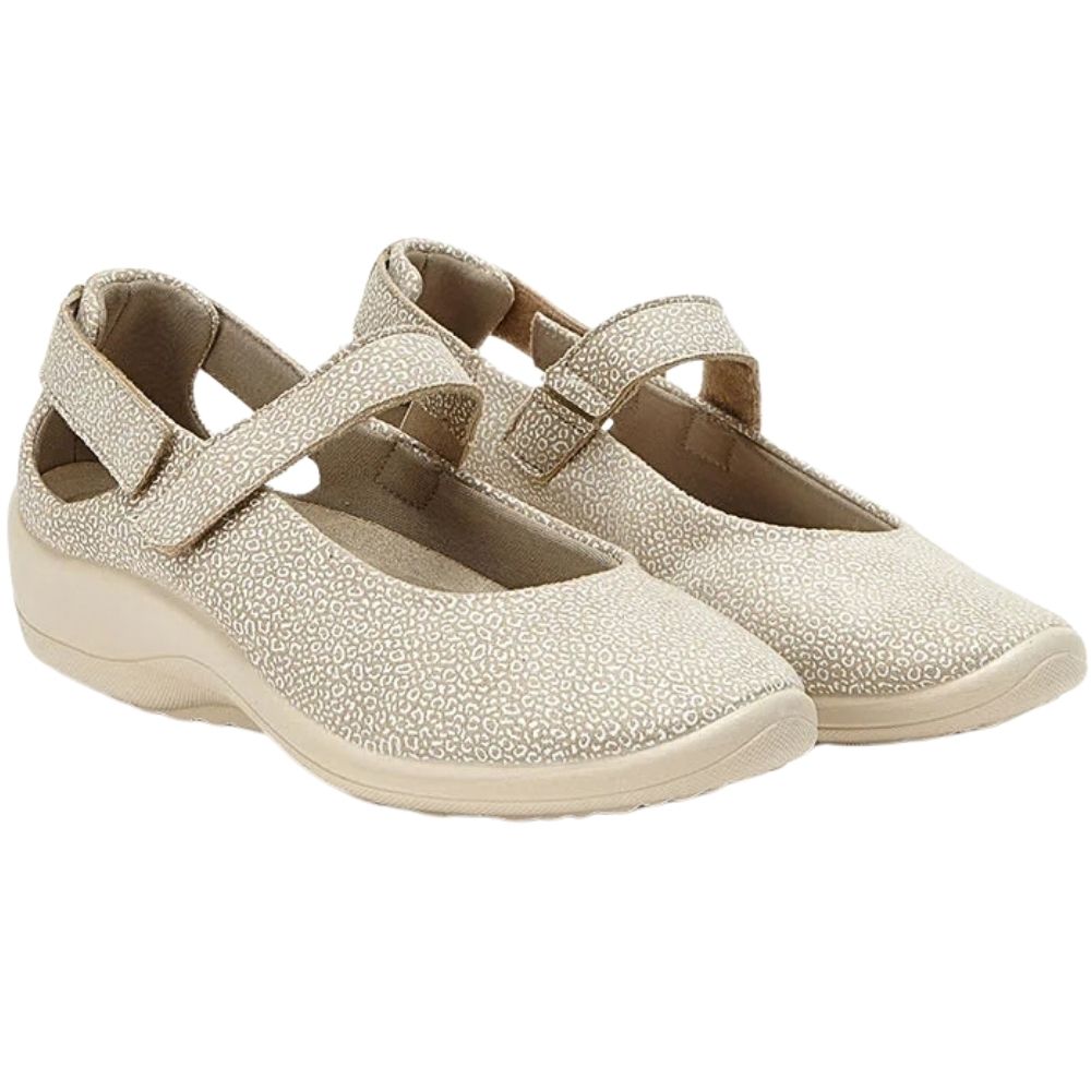 A pair of women's Mary Jane-style slip-on shoes with a speckled textured finish in a light beige color, featuring a wide strap across the instep and a low wedge heel, shown against a plain white background.