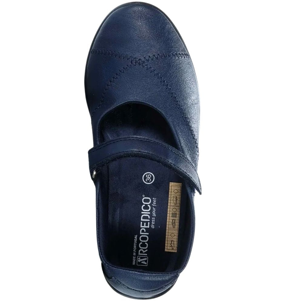 A single navy blue leather Mary-Jane shoe shown from a top-down view on a white background, featuring a Velcro strap closure and the brand name 'ARCOPEDICO' printed on the insole.
