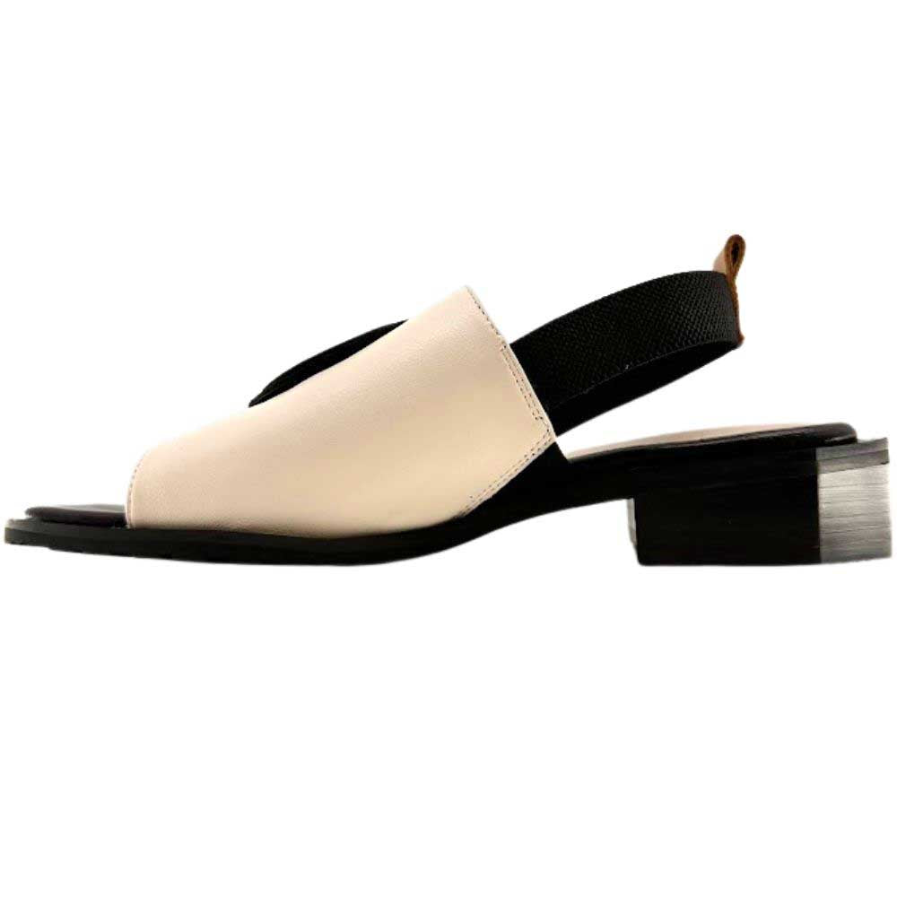 A women's slide sandal with a low block heel, featuring a color-blocked design in cream with a black leather disk detail on the toe strap.