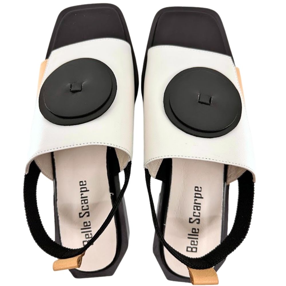 A pair of women's slide sandals featuring a color-blocked design in tan, cream, and black, with a black leather disk detail on the toe straps.