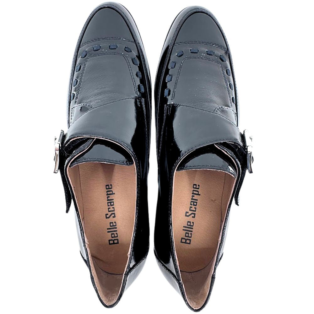 Pair of black patent leather shoes with buckle detail on a white background