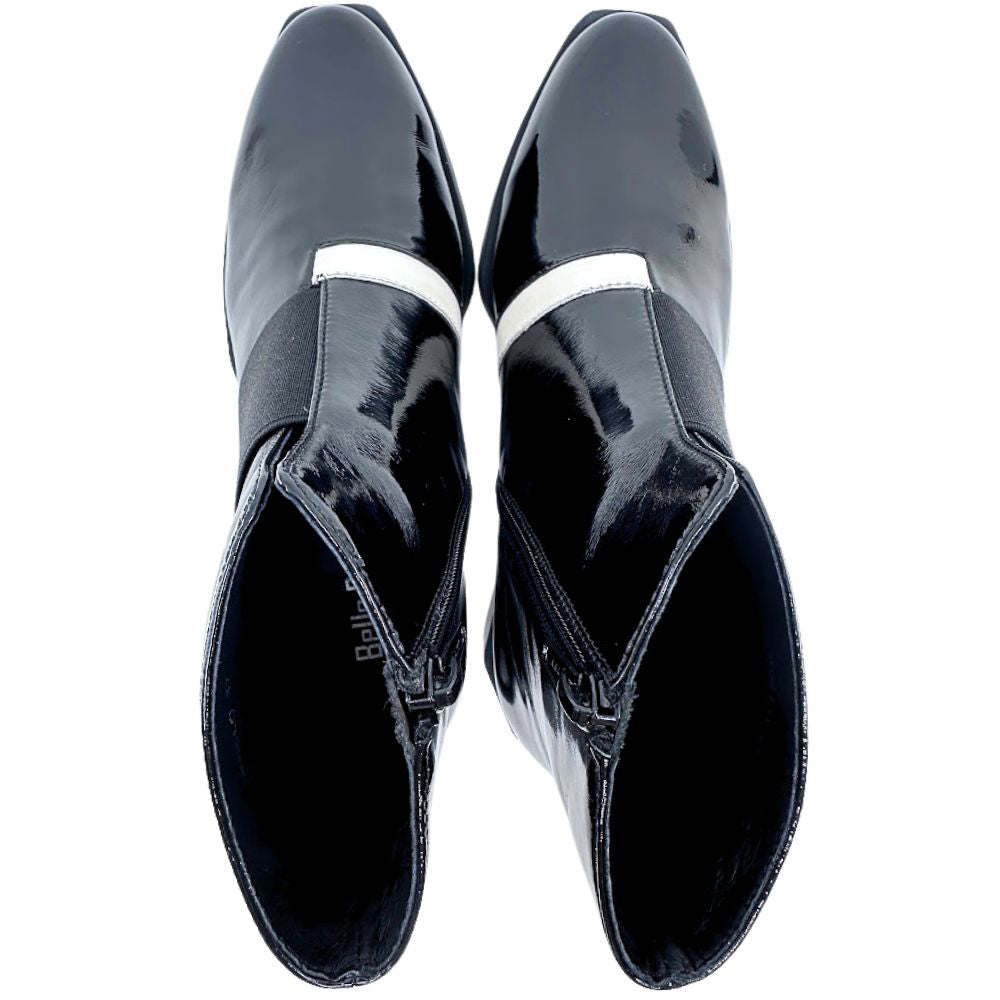 Pair of black patent leather shoes with white trim on a white background