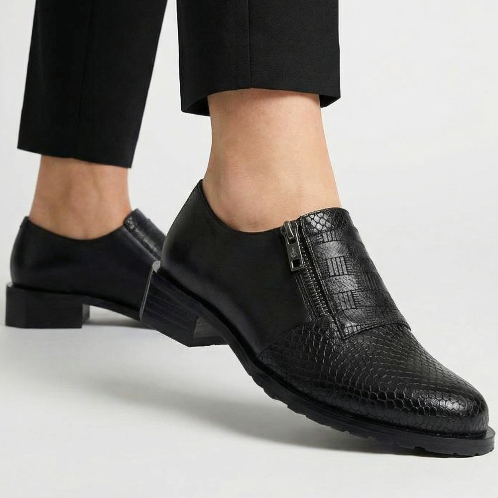 Black leather shoes worn with black pants on a light gray background
