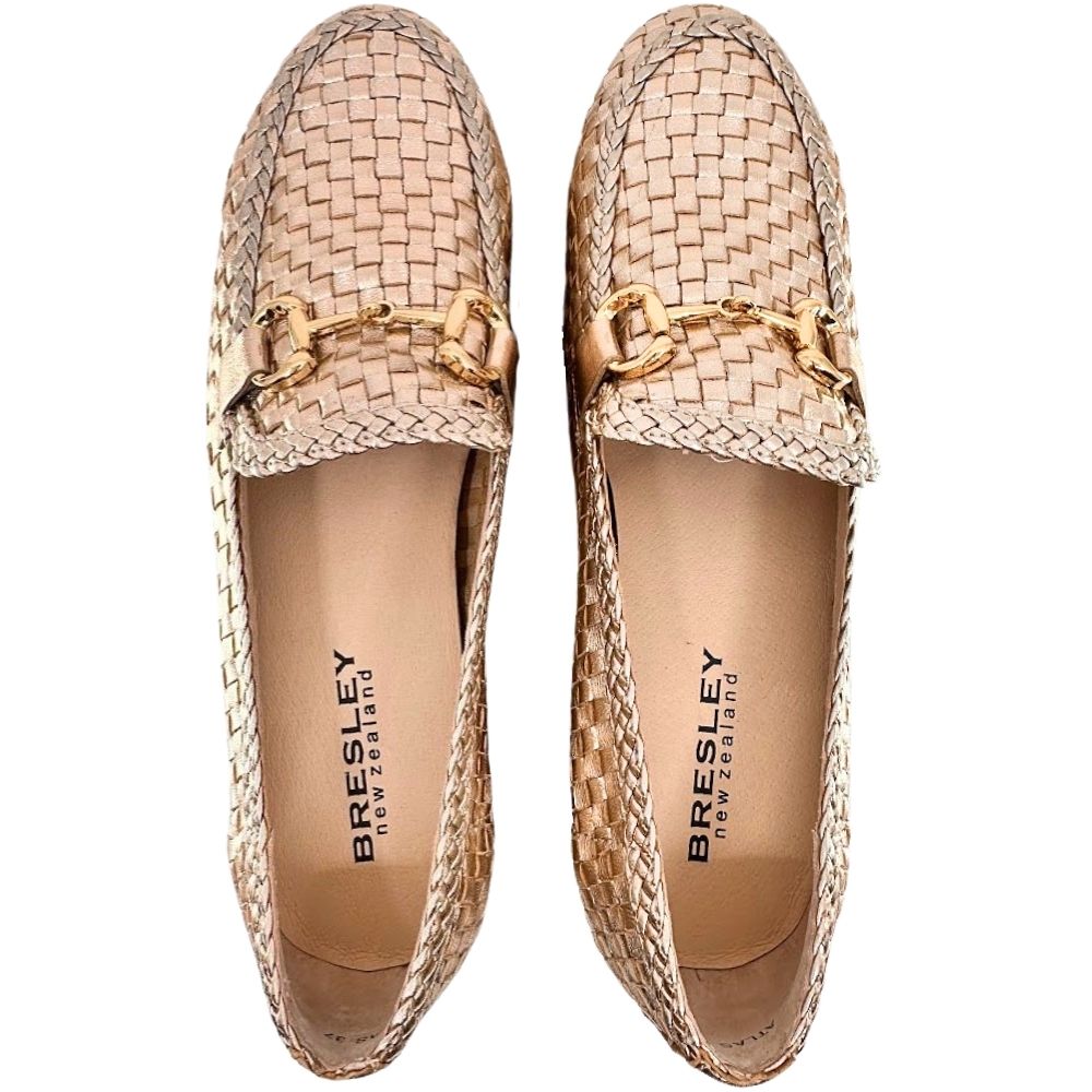 A pair of Bresley New Zealand woven leather loafers in metallic rose gold color, featuring a gold-tone horsebit detail across the vamp and the brand name printed on the insoles, set against a plain white background.