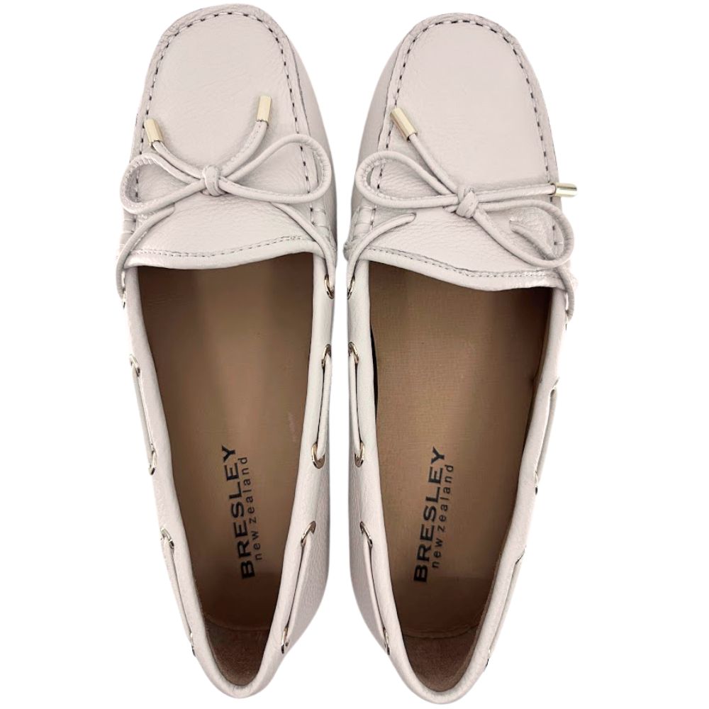 Pair of cream loafers with bow details on a white background