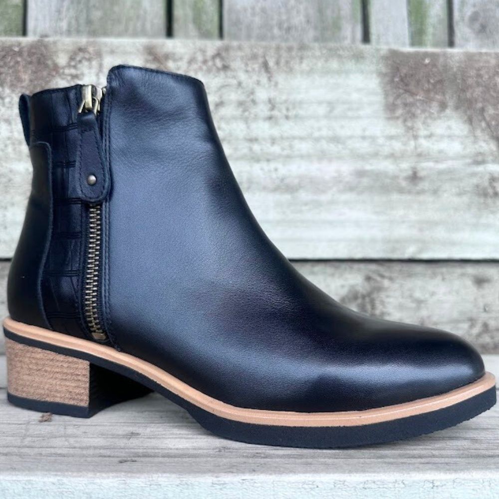 Black leather boot with a block heel on a wooden surface
