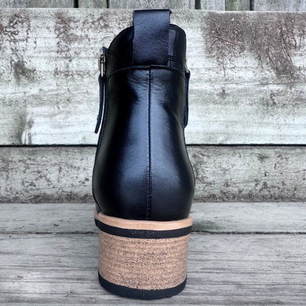 Black ankle boot with cork sole on a wooden surface
