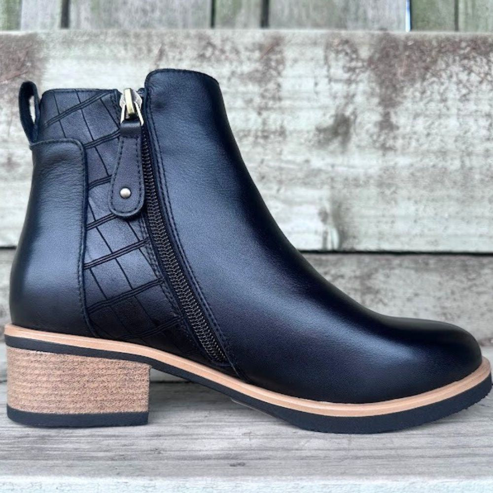 Black leather ankle boot with a block heel on a wooden surface