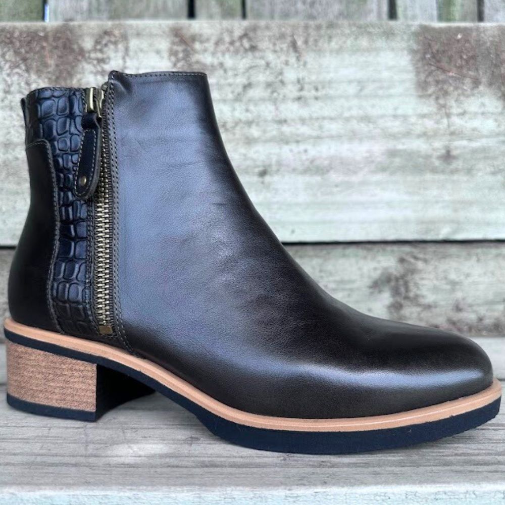 Dark forest green leather ankle boot with a block heel on a wooden surface