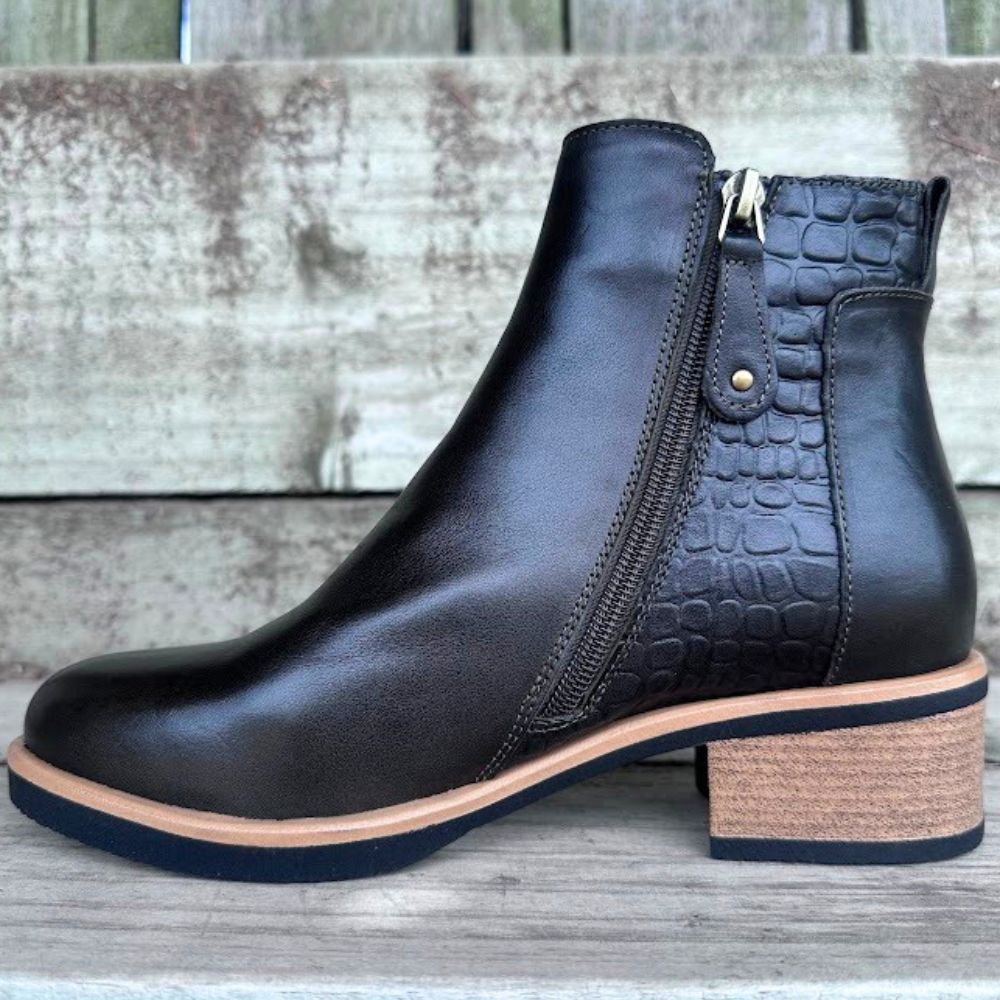 Dark forest green leather ankle boot with a block heel on a wooden surface