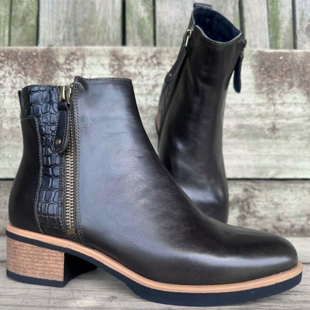 Dark forest green leather ankle boots with a block heel on a wooden surface
