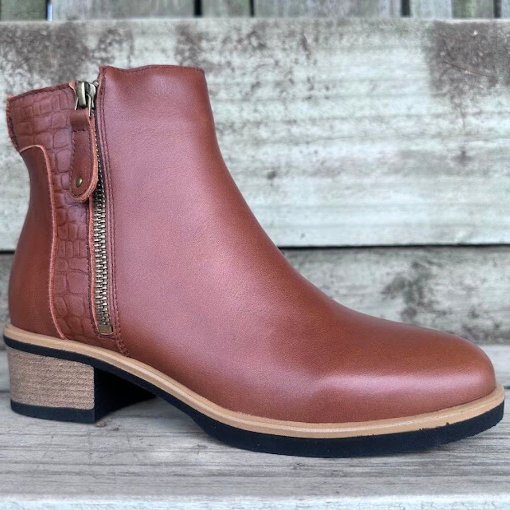 Brown leather ankle boot with a zipper on a wooden surface