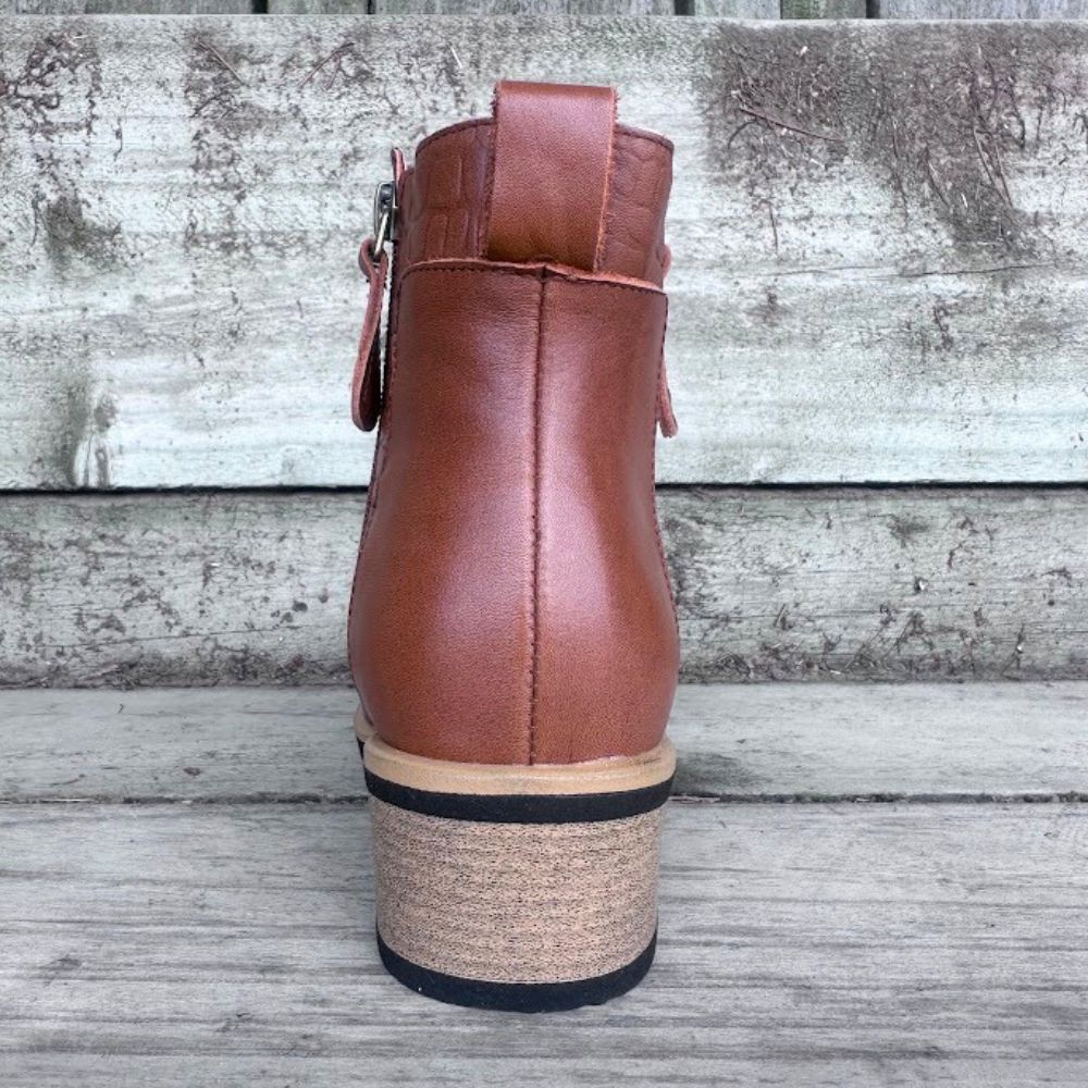 Back of brown leather boot on a wooden surface