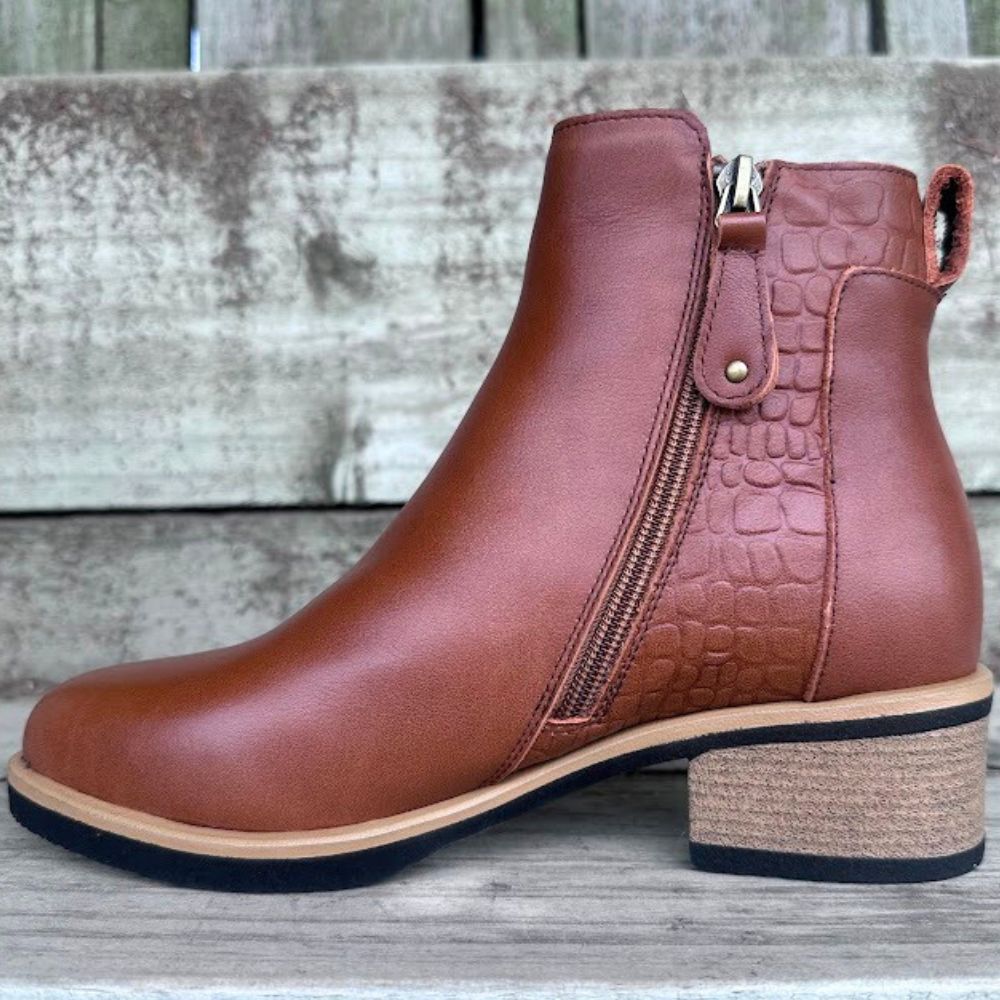 Brown leather ankle boot with a crocodile texture on a wooden surface