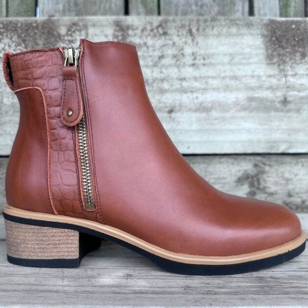 Brown leather ankle boot with a zipper on a wooden surface