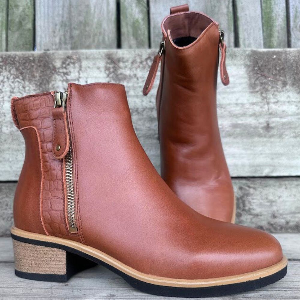 Pair of brown leather ankle boots with zippers on a wooden surface