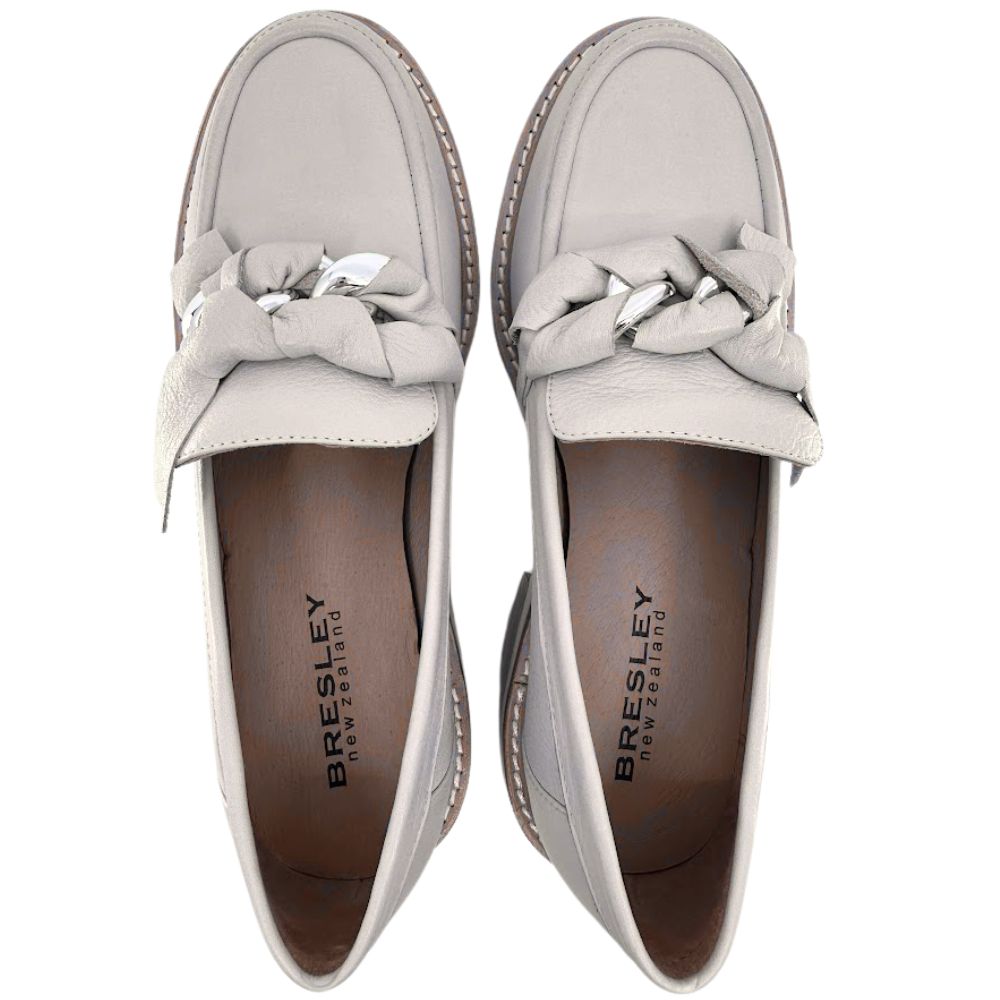 Pair of cream loafers with decorative bows on a white background