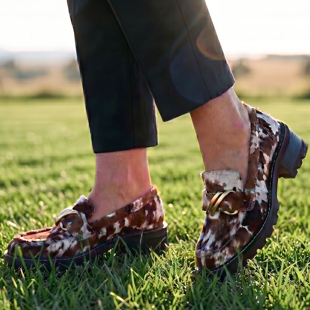 Person wearing textured animal print loafers on grass