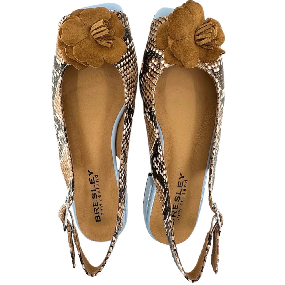 A pair of Bresley peep-toe slingback flats featuring a snakeskin pattern in beige, brown, and black, adorned with a large tan suede flower on the toe.