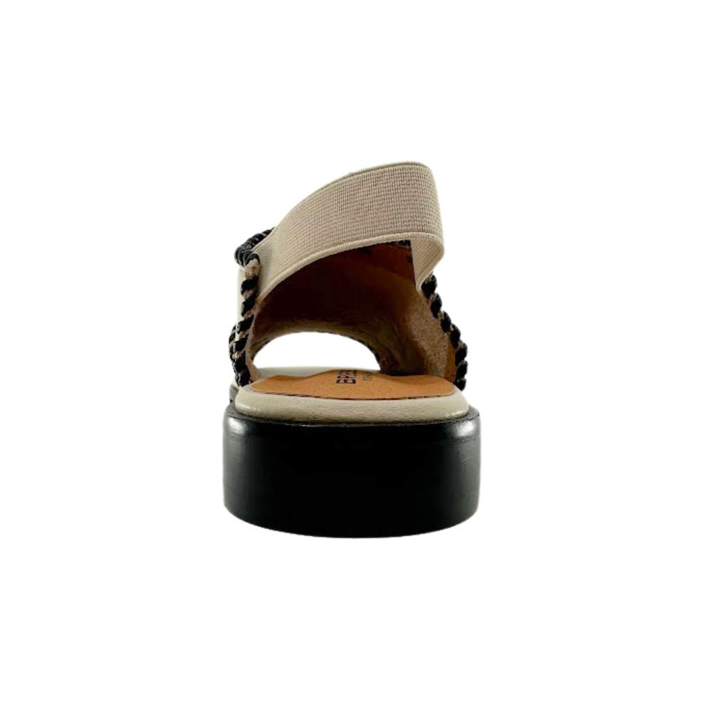 A single sandal shown from a rear three-quarter view, featuring a black heel, a cream woven upper strap, and black braided detailing along the edges.