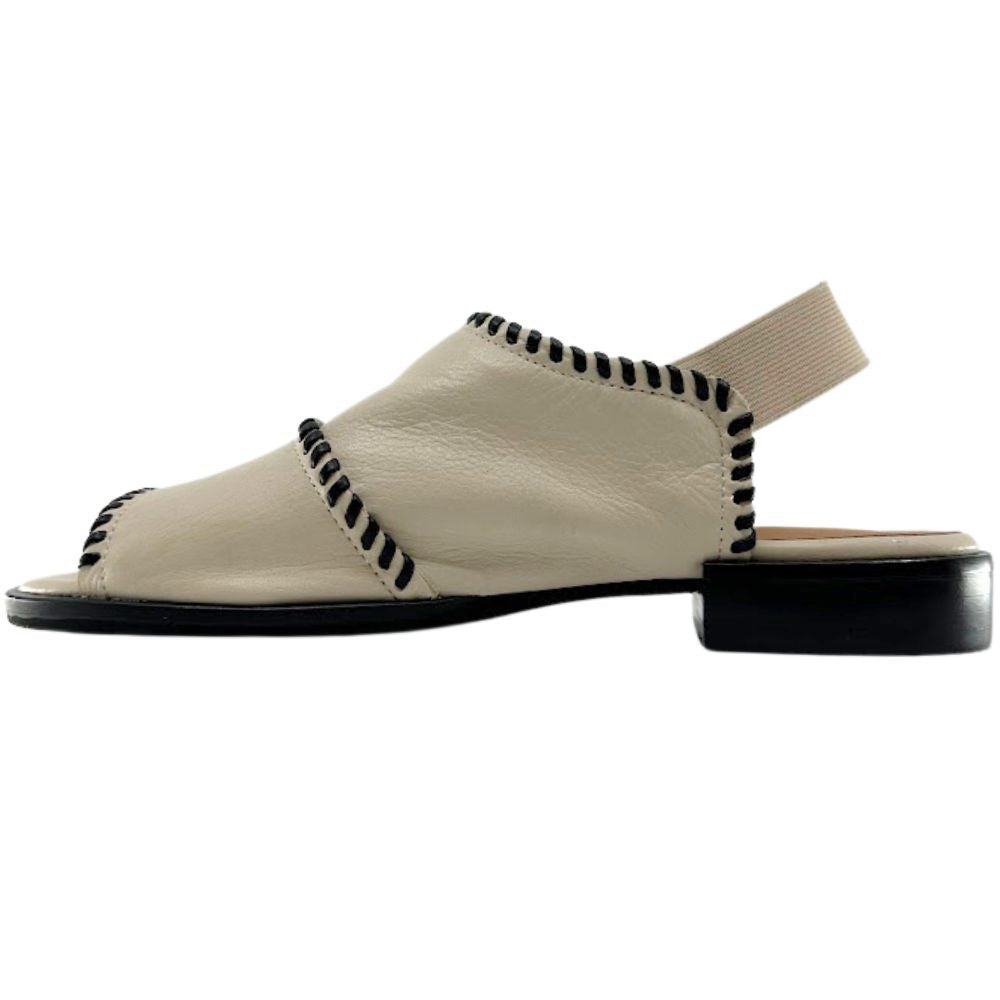 A single cream leather slide sandal with black contrast stitching along the straps and a black sole, shown in a side profile on a white background.
