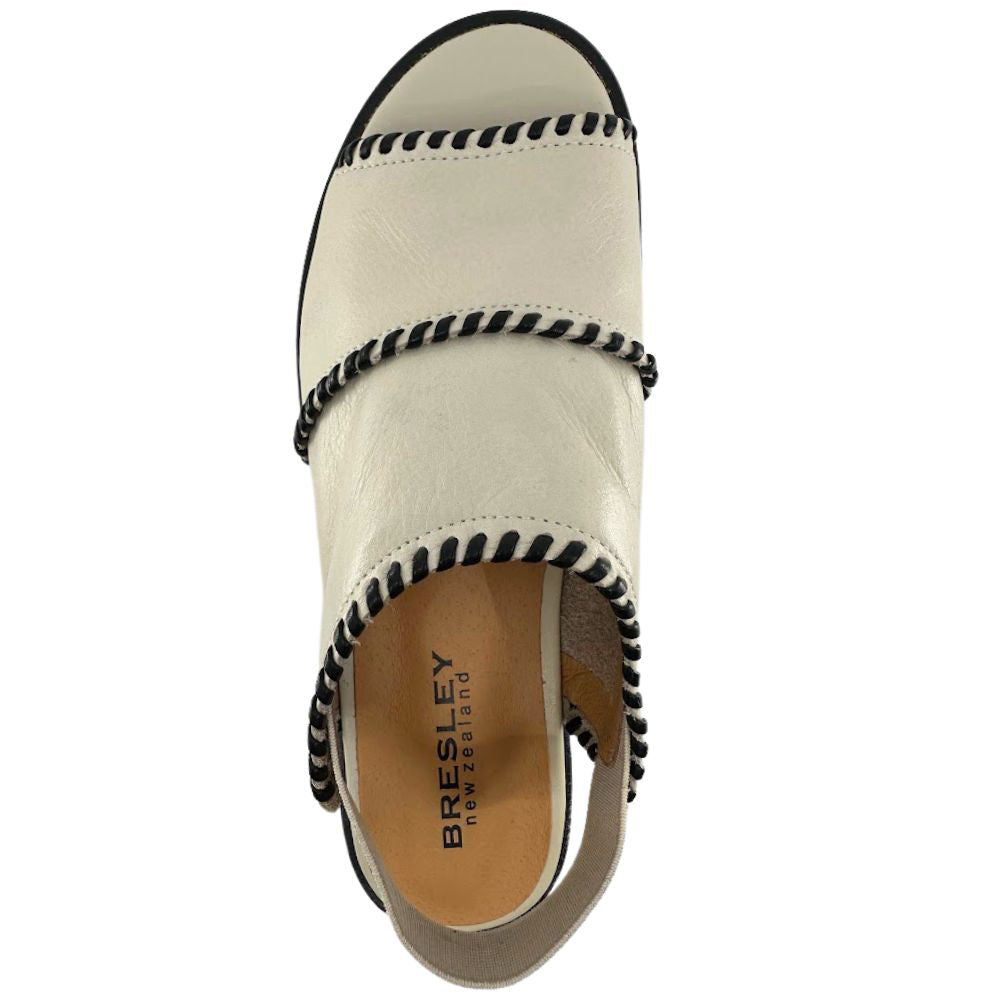 A single women's cream leather sandal shown from a top-down view on a white background. The shoe features an off-white leather upper with black whipstitching along the edges, a black outsole edge, and a tan insole with the brand name 'BRESLEY new zealand' printed on it.