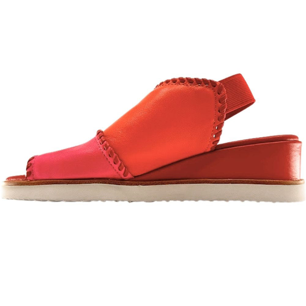 A woman's wedge sandal in vibrant shades of coral orange, hot pink, and red, with braided trim and a rear elastic back strap, shown from an inside view on a white background.