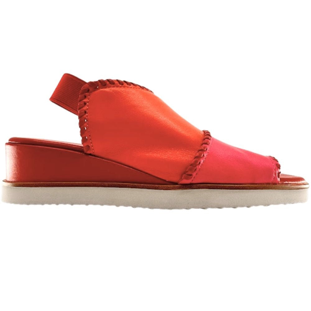 A woman's wedge sandal in vibrant shades of coral orange, hot pink, and red, with braided trim and a white outsole, shown against a white background.