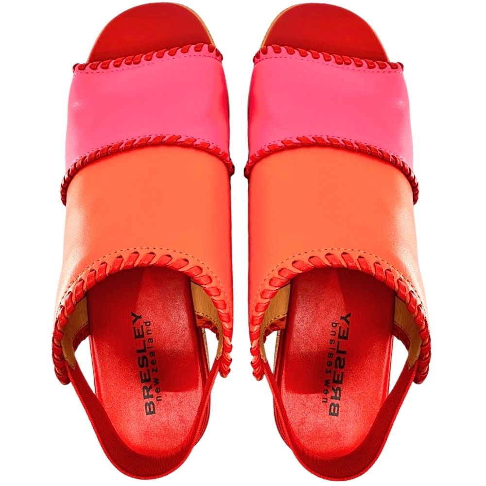 A pair of women's wedge sandals in vibrant shades of coral orange, hot pink, and red with braided trims and elastic rear back straps, shown from a top-down perspective on a white background.