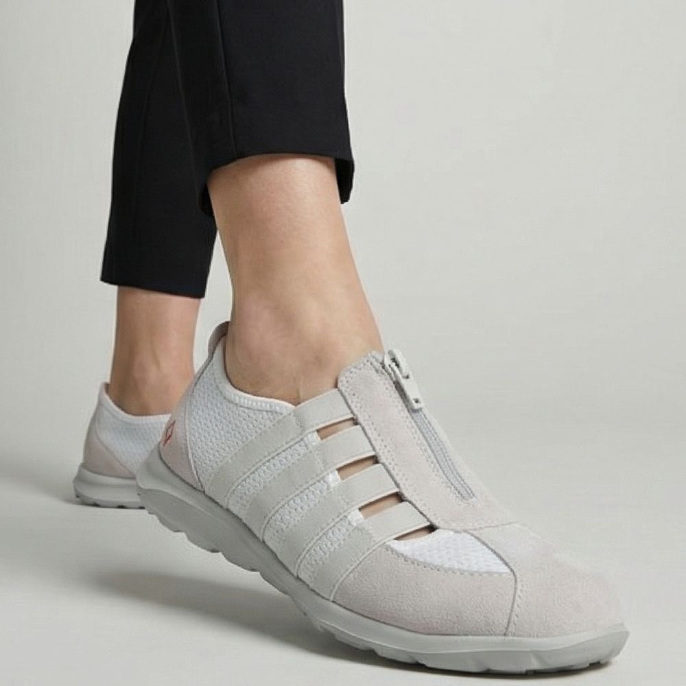 Cream casual shoes worn with black pants on a neutral background