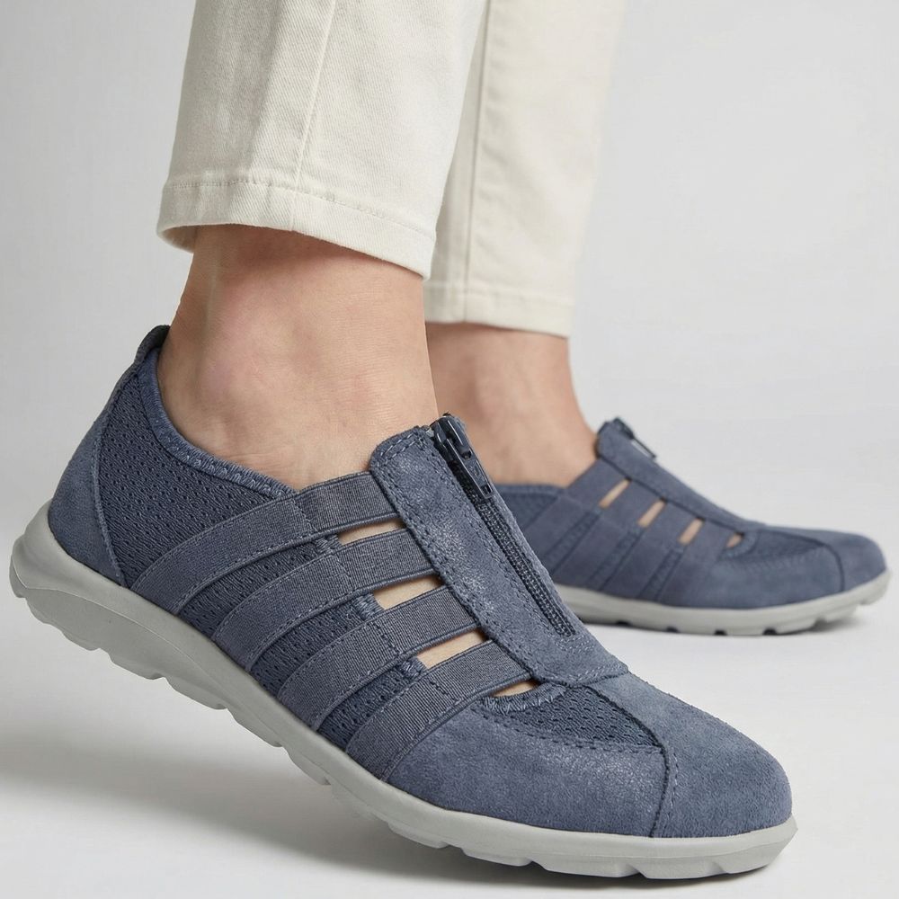 Denlm blue casual shoes worn with light-colored pants on a neutral backgroundm 