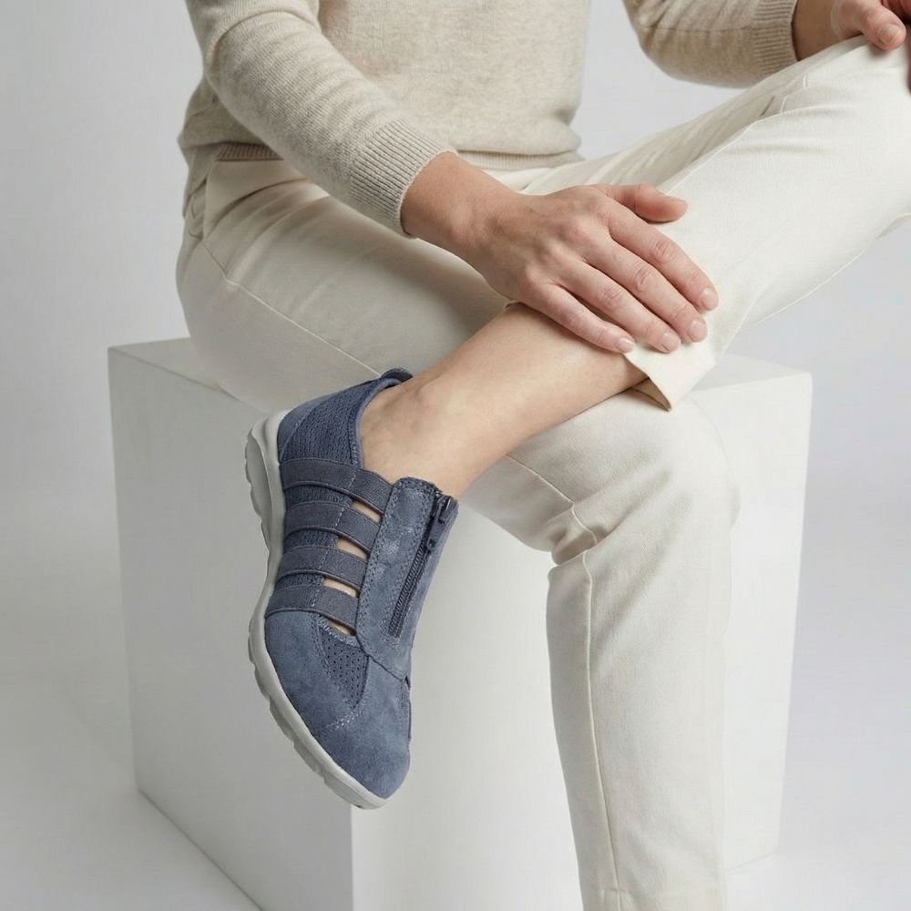 Person wearing blue denim slip-on shoes with a neutral background