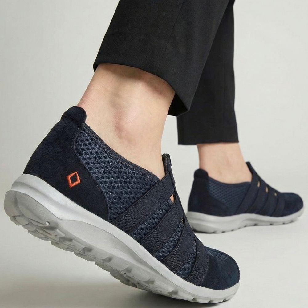 Navy slip-on shoes with grey soles worn by a person on a light gray background