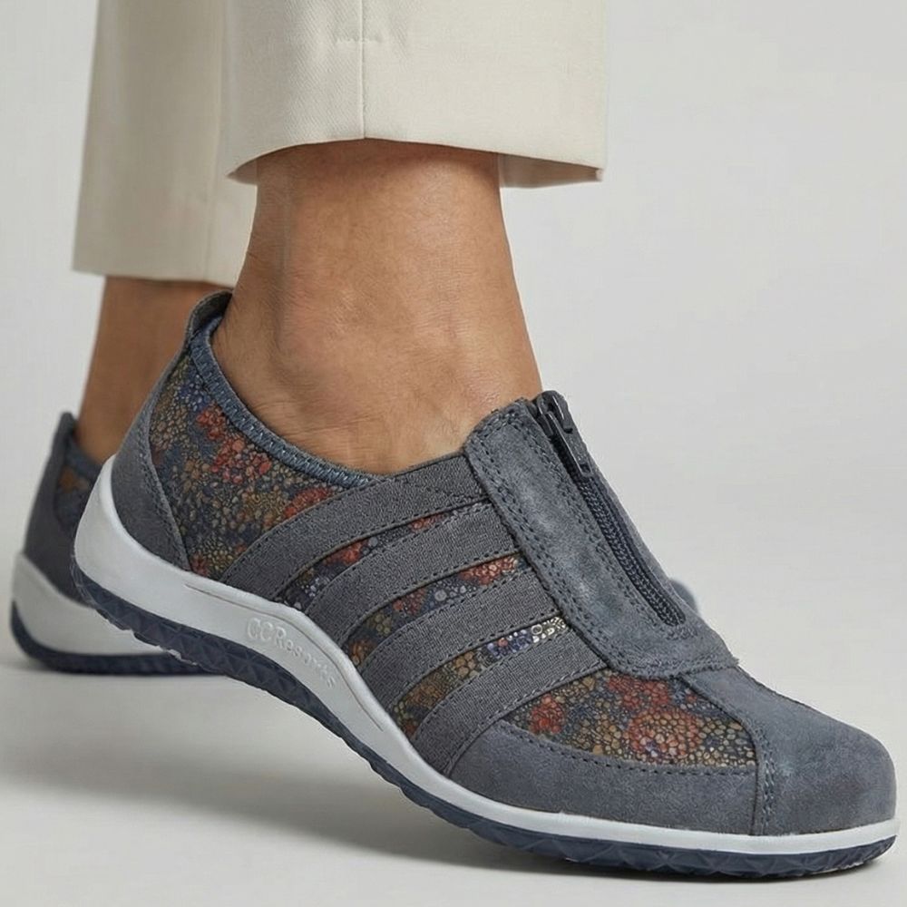 Blue shoe with floral accents and central zip worn by a person on a light background