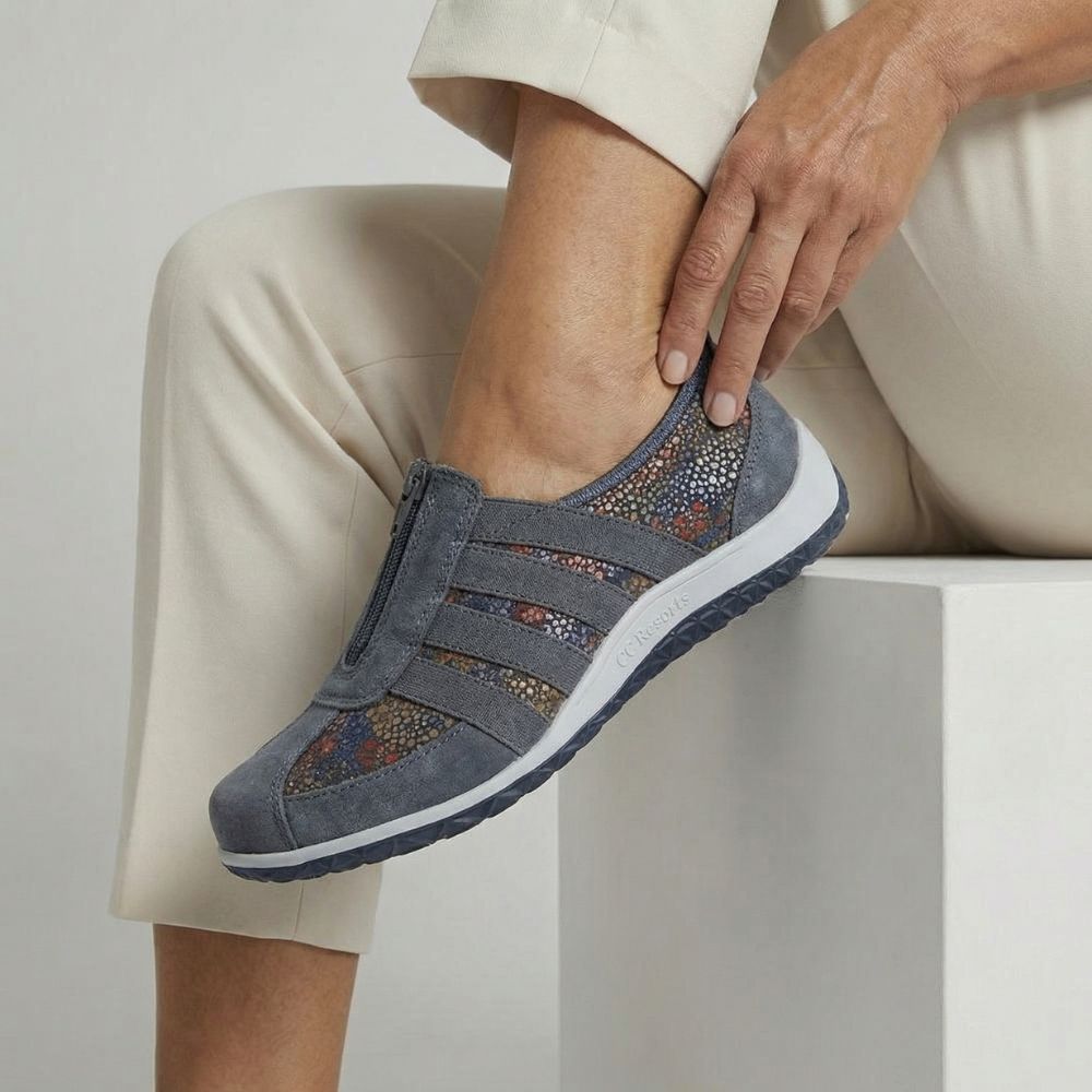 Person wearing a blue slip-on shoe with decorative patterns on a light background