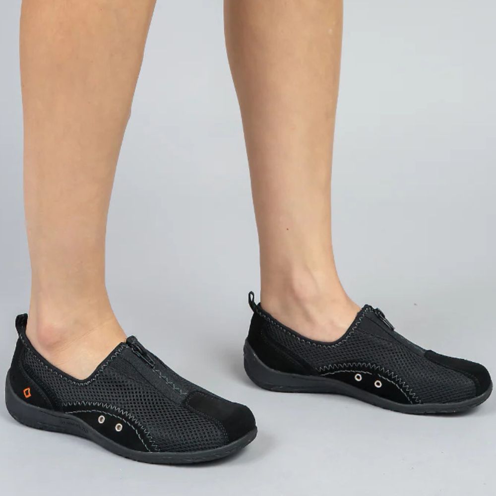 Black casual shoes worn by a person on a light gray background