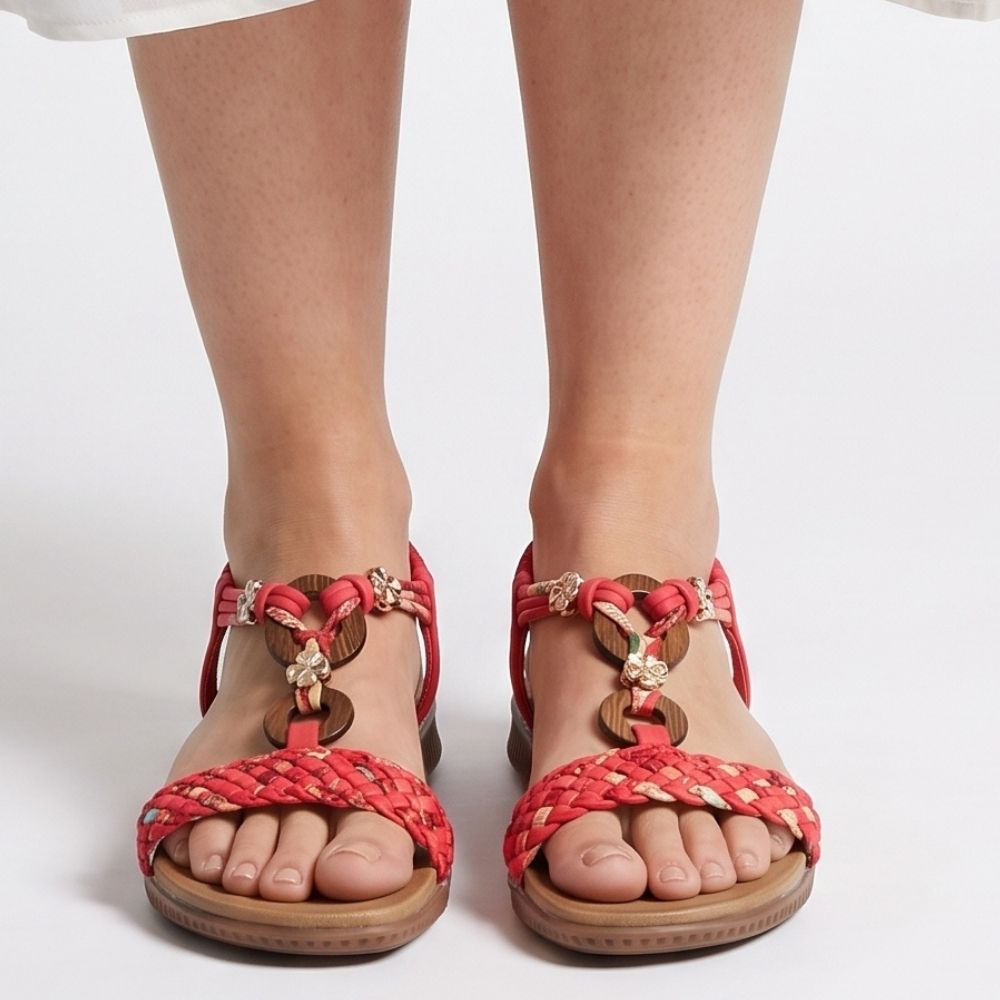 Red woven sandals with gold-tone hardware and brown soles, shown on a model's feet against a white studio background.