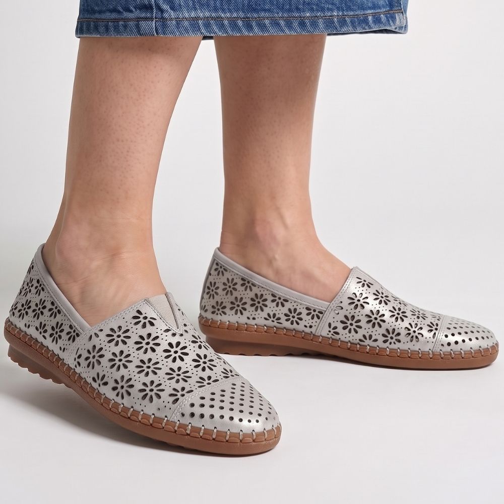  A lady in a denim skirt wearing a pair of taupe laser-cut Cabello leather loafers with a central elastic gusset and brown rubber sole, standing against a studio background.