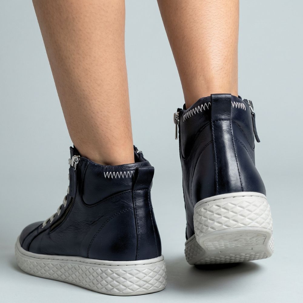 Black leather ankle boots with white soles on a light gray background