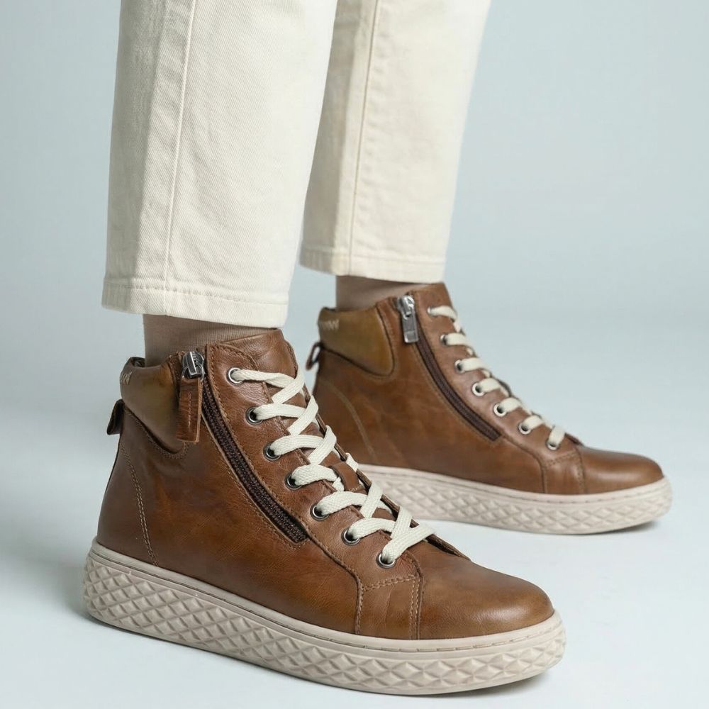 Tan leather ankle boots with beige laces on a light gray background