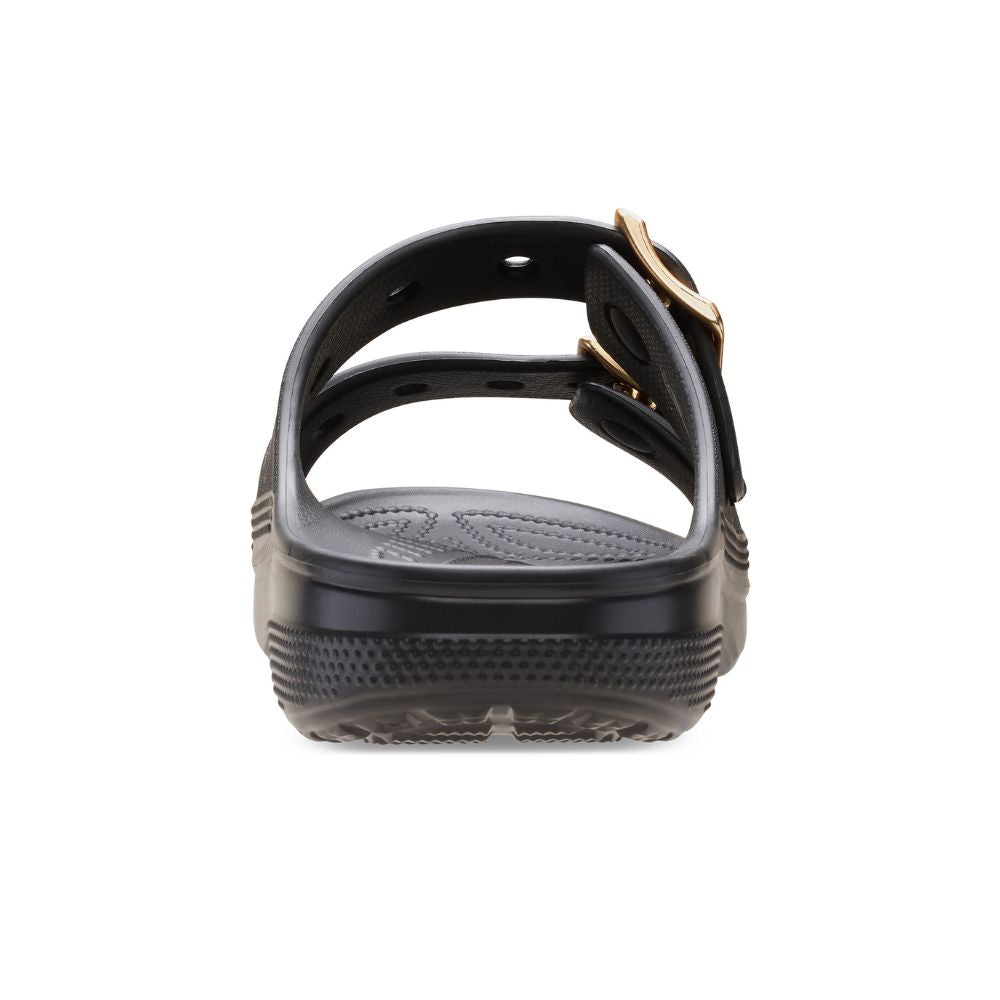 A single black slide sandal shown from a rear three-quarter view, featuring a thick textured sole and double straps with gold-tone buckles, set against a plain white background.