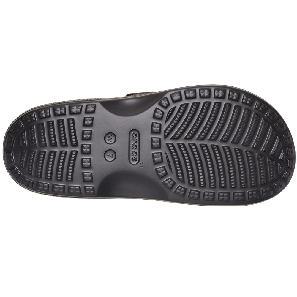 The black textured rubber outsole of a Crocs slip-on shoe, showing the brand name and size markings, isolated on a white background.