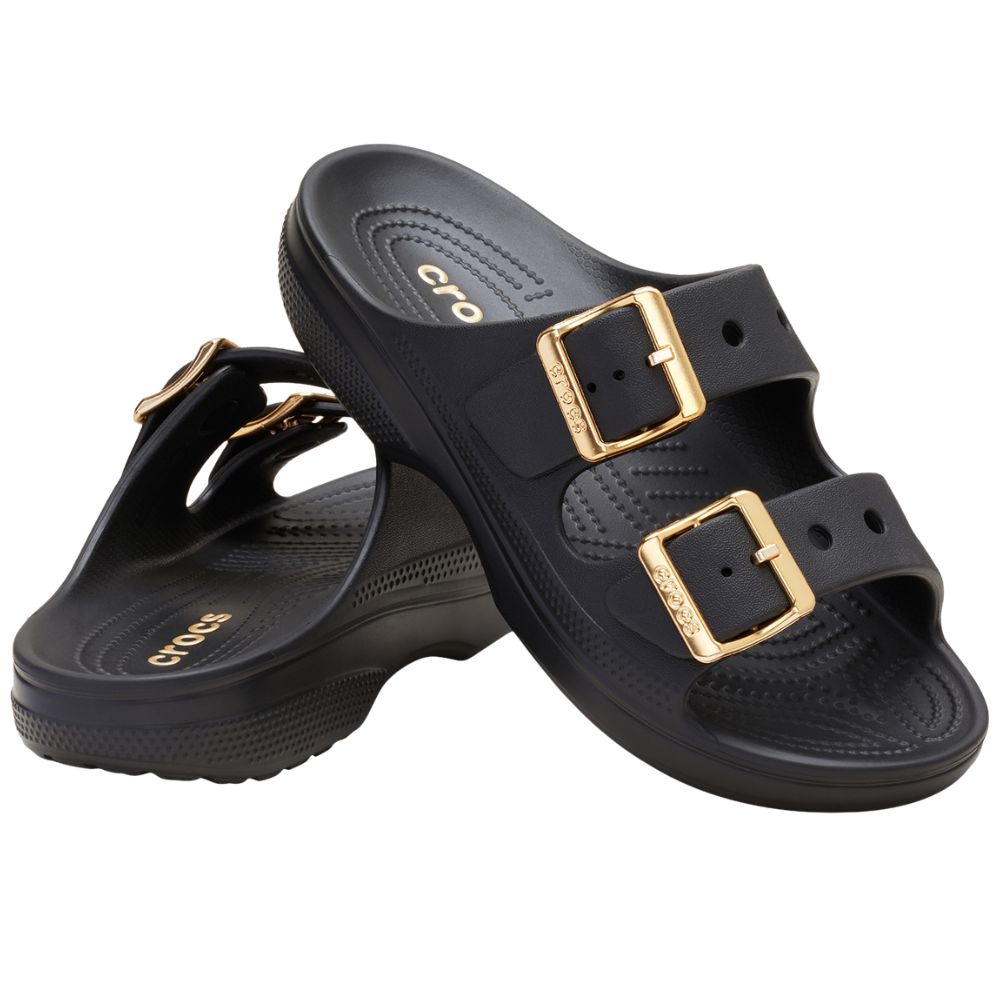A pair of black Crocs double-strap slide sandals with gold-tone buckle hardware, shown on a plain white background.